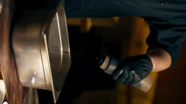 Merkezi salondaki kaburga barındaki bir restoranda dikey video kaset siyah eldivenli şef çeşitli baharatlarla dolu bir demir kutuya çiğ domuz eti serpiyor.