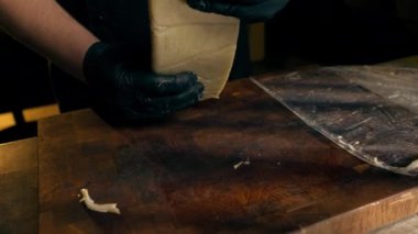 Merkezdeki kaburga barında yakın bir restoranda ahşap bir tahtanın üzerinde siyah eldivenli bir şef peyniri peynir çubuğu yapmak için şeritlere ayırıyor.