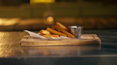 Lokantada, demir bir masanın üzerinde, ahşap bir tahtanın üzerinde, üzerinde çıtır çıtır bir kağıt olan, soslu peynirli çubuklardan oluşan hazır bir tabak.