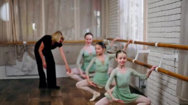 Profesyonel bale okulu. Barda antrenör eğitimi almış yeşil elbiseli kızlar.
