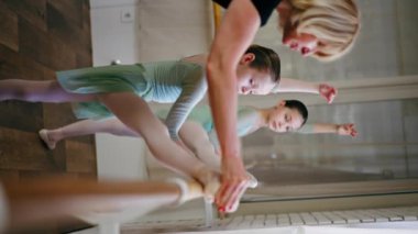 Dikey video profesyonel bale okulu. Barda antrenörlük eğitimi almış yeşil elbiseli kızlar için.