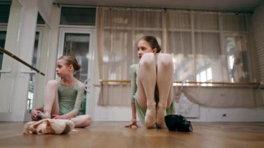 Çocuklar için profesyonel bir bale okulu. Yerde poz vererek ısınıyorlar.