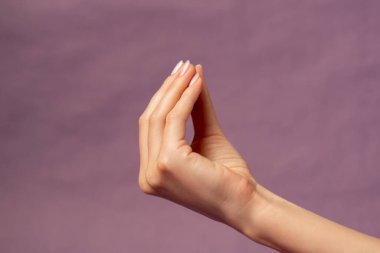 Mor arka planda izole edilmiş güzel bir kadın eli. Çıplak manikür el, çatışmada tatminsizlik gösteriyor.