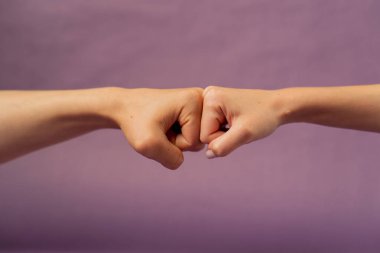Güzel bir kadın eli mor arka planda izole edilmiş. Yumruk yumruğa işaret dilini desteklemek için iki el.