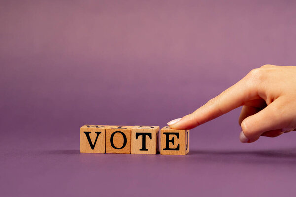 фиолетовый теплый фон с тенями женщина рука положить деревянные кубики с черными буквами положил слово голосование