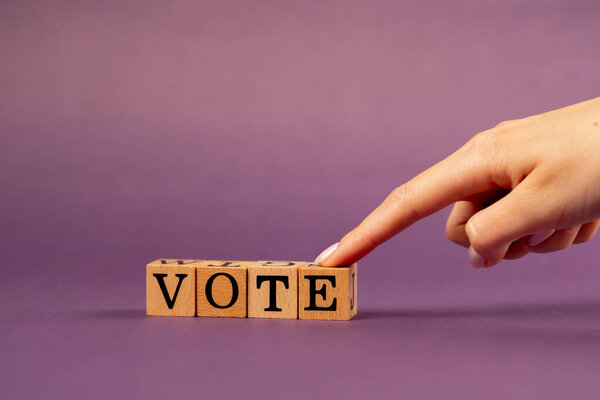 фиолетовый теплый фон с тенями женщина рука положить деревянные кубики с черными буквами положил слово голосование