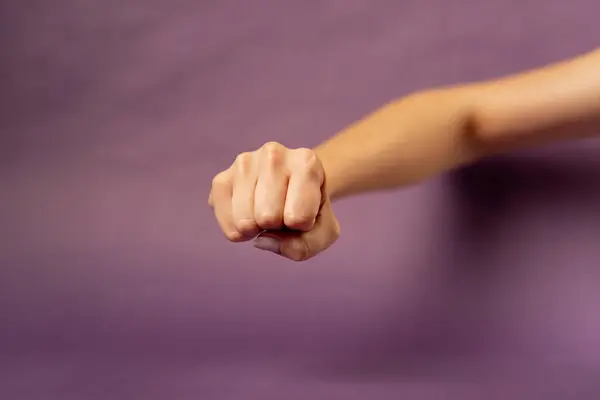 stock image Beautiful female hand on isolated on purple background sign language folded hand into fist at camera