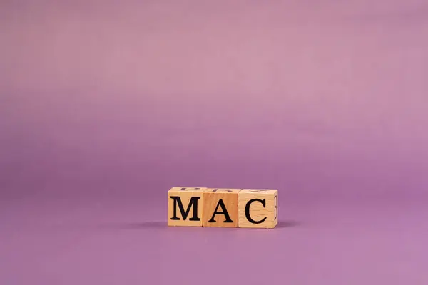 stock image violet warm background with shadows woman hand put wooden cubes with black letters laid out word Mac