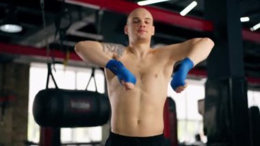 Bir boks kulübüne yakın plan mavi bandajlı kel genç bir boksör gölge boksu profesyonel tekniğini yumrukluyor.