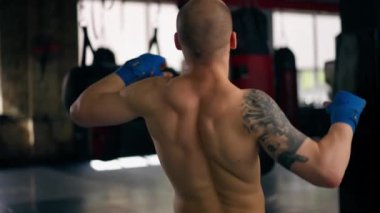 Bir boks kulübüne yakın plan mavi bandajlı kel genç bir boksör gölge boksu profesyonel tekniğini yumrukluyor.