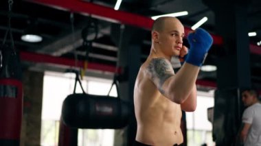 Bir boks kulübüne yakın plan mavi bandajlı kel genç bir boksör gölge boksu profesyonel tekniğini yumrukluyor.