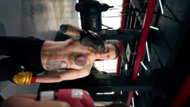 Bir boks kulübünde dikey video. Siyah kazaklı genç bir kız. Pembe eldivenli.