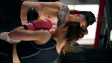 Bir boks kulübünde dikey video. Siyah kazaklı genç bir kız. Pembe eldivenli.