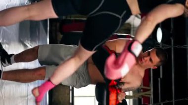 Bir boks kulübünde dikey video. Siyah kazaklı genç bir kız. Pembe eldivenli.