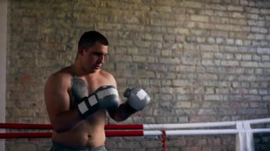 Bir boks kulübünde dövmeleri gri eldivenli genç bir boksör. Trenler, kombo yumruklar, dövüş tekniklerinde profesyonel sınıf eğitimi.