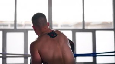 Bir boks kulübünde. İki çıplak göğüslü boksör. Gri eldivenli dövmeli.