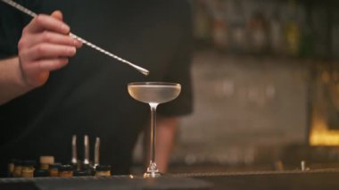 Profesyonel bir barmen barın üstünde buzlu beyaz bir kokteyl karıştırır.