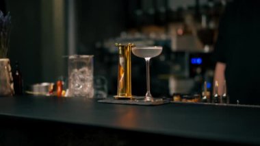 Bar tezgahında serinletici bir bardak var yanında da martini ve altın bir kum saati.