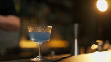 Barda duran mavi içki bardağı pembe köpükle dolduruyor.