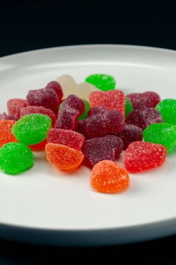 Beyaz bir tabağa yakın çekim çok renkli tatlı jöleler serpiştirilmiş şeker çeşitli meyveler çocuklar için lezzetli