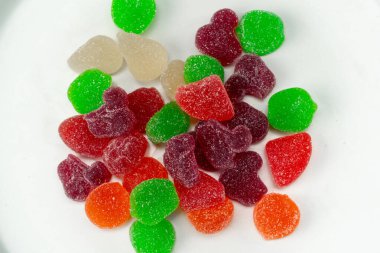 Beyaz bir tabağa yakın çekim. Çok renkli tatlı jöleler, çeşitli meyveler serpiştirilmiş. Çocuklar için bir lezzet.