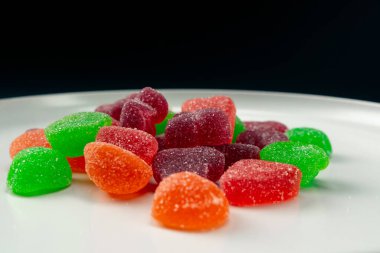 Beyaz bir tabağa yakın çekim çok renkli tatlı jöleler serpiştirilmiş şeker çeşitli meyveler çocuklar için lezzetli