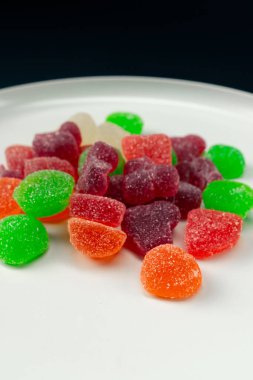 Beyaz bir tabağa yakın çekim çok renkli tatlı jöleler serpiştirilmiş şeker çeşitli meyveler çocuklar için lezzetli
