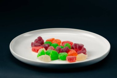 Beyaz bir tabağa yakın çekim çok renkli tatlı jöleler serpiştirilmiş şeker çeşitli meyveler çocuklar için lezzetli