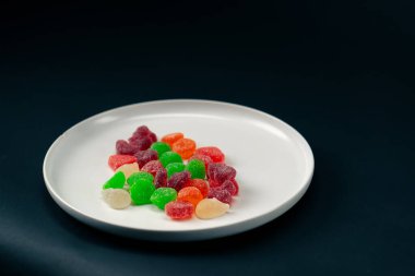 Beyaz bir tabağa yakın çekim çok renkli tatlı jöleler serpiştirilmiş şeker çeşitli meyveler çocuklar için lezzetli