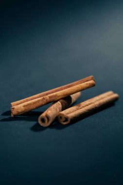 Siyah ve mavi arka plan baharatlarına yakın çekim. Kahverengi tarçınlı çubuklar kahve ve sıcak şarap için tatlandırıcı.