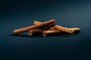 Siyah ve mavi arka plan baharatlarına yakın çekim. Kahverengi tarçınlı çubuklar kahve ve sıcak şarap için tatlandırıcı.