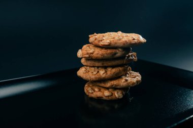 Siyah ve mavi arka planda düz siyah bir tabakta. Piramit şeklinde kurabiyeler var. Mutfak temiz.