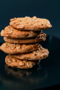 Siyah ve mavi arka planda düz siyah bir tabağa yakın. Piramit şeklinde kurabiyeler, tatlı bir mutfak, temiz bir alan.