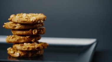 Siyah ve mavi arka plan düz bir tabağa yakın. Piramidin içine yerleştirilmiş kurabiye kurabiyeleri ve dağınık mutfak fıstıkları.