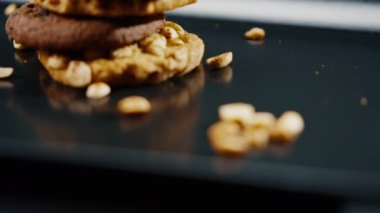 Siyah ve mavi arka plan düz bir tabağa yakın. Piramidin içine yerleştirilmiş kurabiye kurabiyeleri ve dağınık mutfak fıstıkları.