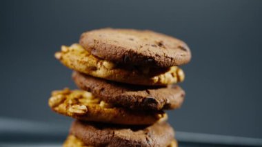 Siyah ve mavi arka plan düz bir tabağa yakın. Piramidin içine yerleştirilmiş kurabiye kurabiyeleri ve dağınık mutfak fıstıkları.