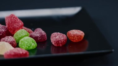 Siyah, uzun bir tabakta çok renkli tatlı bir jöle serpiştirilmiş şeker çeşitli meyveler çocuklar için lezzetlidir.