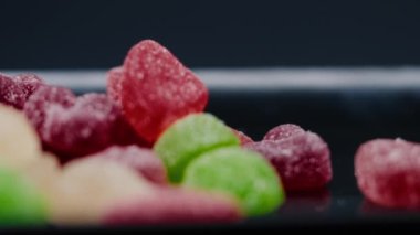 Siyah, uzun bir tabakta çok renkli tatlı bir jöle serpiştirilmiş şeker çeşitli meyveler çocuklar için lezzetlidir.