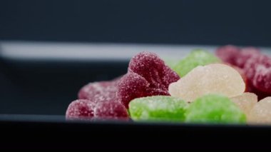 Siyah, uzun bir tabakta çok renkli tatlı bir jöle serpiştirilmiş şeker çeşitli meyveler çocuklar için lezzetlidir.