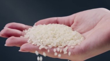 Siyah ve mavi arka planda siyah uzun düz tabakta beyaz yuvarlak pirinç vardır Japon kültürü hafif protein yiyeceği bir kadının eli tabağa pirinç döker.