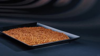 Karabuğday, siyah, uzun düz bir tabakta, siyah, mavi bir zemin üzerinde uzanıyor. Ukrayna kültüründe hafif protein yiyeceği.