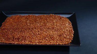 Karabuğday, siyah, uzun düz bir tabakta, siyah, mavi bir zemin üzerinde uzanıyor. Ukrayna kültüründe hafif protein yiyeceği.