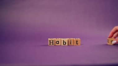 Kadın eli gölgeli menekşe sıcacık arka plan. Siyah harfli ahşap küpler. Kelime alışkanlıkları.