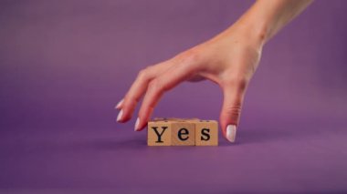 Menekşe sıcacık arka plan, gölgeli kadın eli, siyah harfli ahşap küpler, evet.