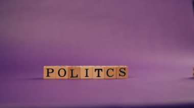 Kadın eli gölgeli menekşe sıcacık arka plan. Siyah harfli tahta küpler. Politika berbattır.