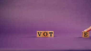 Kadın eli gölgeli menekşe sıcacık arka plan. Siyah harfli tahtadan küpler.