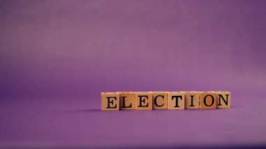 Kadın eli gölgeli menekşe sıcacık arkaplan. Seçim için siyah harflerle yazılmış tahta küpleri yerleştirdi.