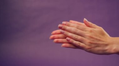 Güzel bir kadın eli mor arka planda izole edilmiş işaret dili alkış eli başka bir çıplak maniküre çarpıyor.