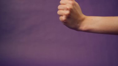 Güzel bir kadın eli mor arka planda izole edilmiş çıplak manikür elinde çatışma işaret parmağında tatminsizlik var.