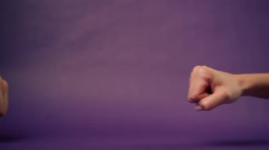 Güzel bir kadın eli mor arka planda izole edilmiş. Yumruk yumruğa işaret dilini desteklemek için iki el.